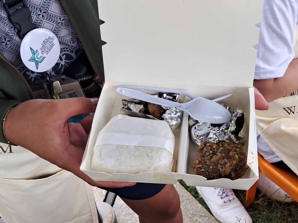 a paper box containing cooked food and plastic utensils