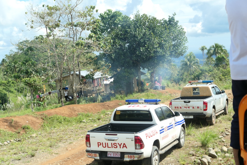 two pickup trucks, one marked "rescue" and one marked "Pulisya" parked on a dirt road